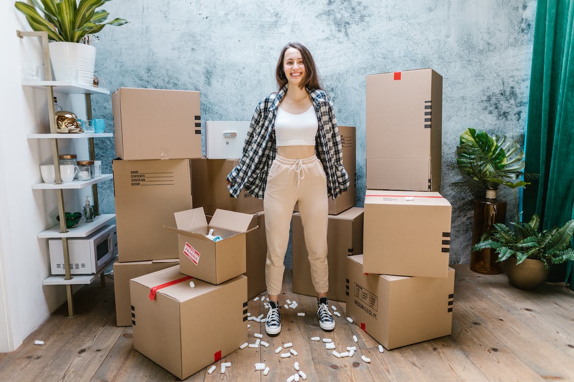 Free Photo of a Woman in a White Crop Top Standing Beside Cardboard Boxes Stock Photo